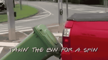 A ute driving on a road with a rubbish bin attached to the back