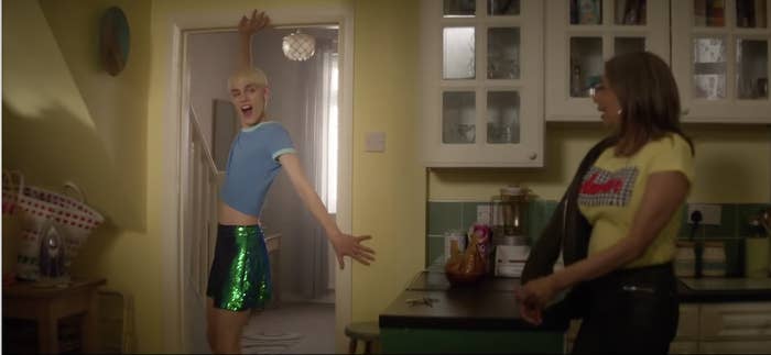 A young man shows off a t-shirt and skirt combo. 