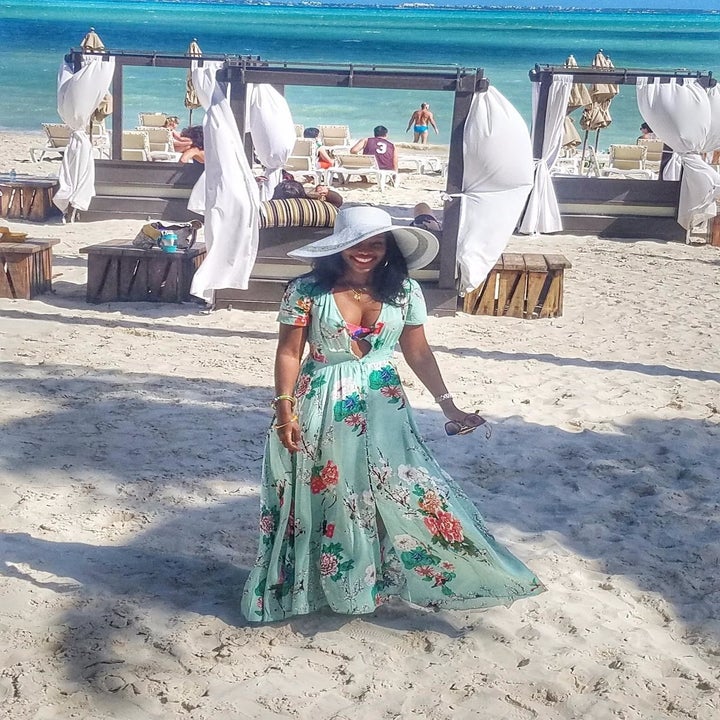 image of reviewer wearing the A green milumia floral maxi dress at a sandy beach resort