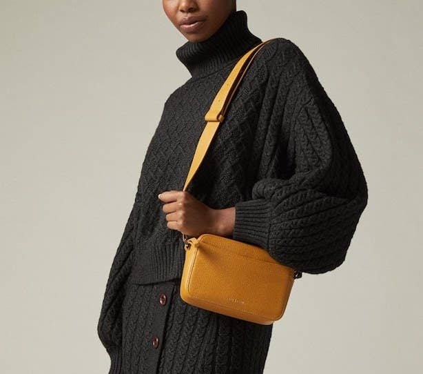 A person in a knit outfit carrying the crossbody bag 