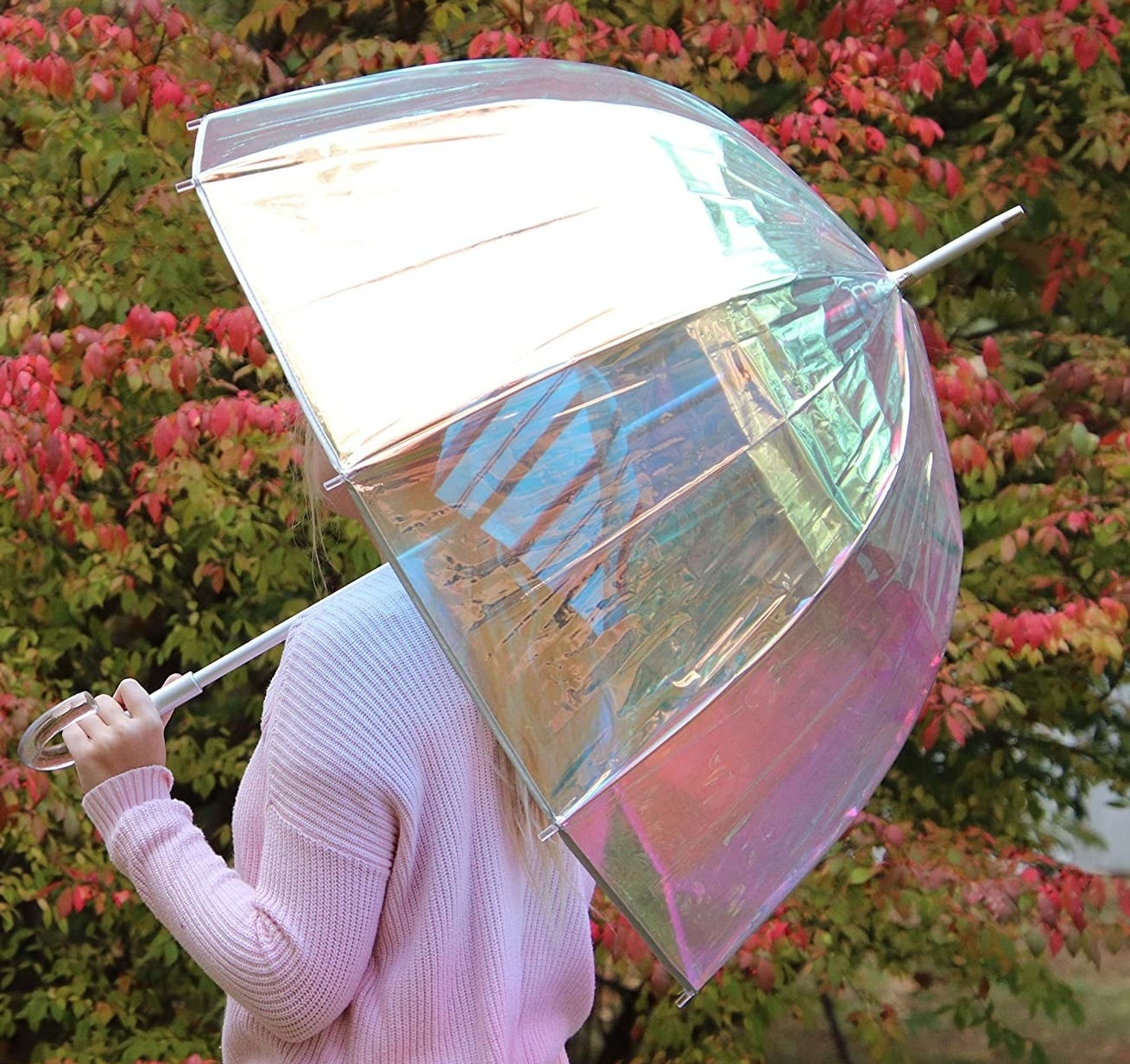 A person holding the holographic bubble umbrella outdoors 