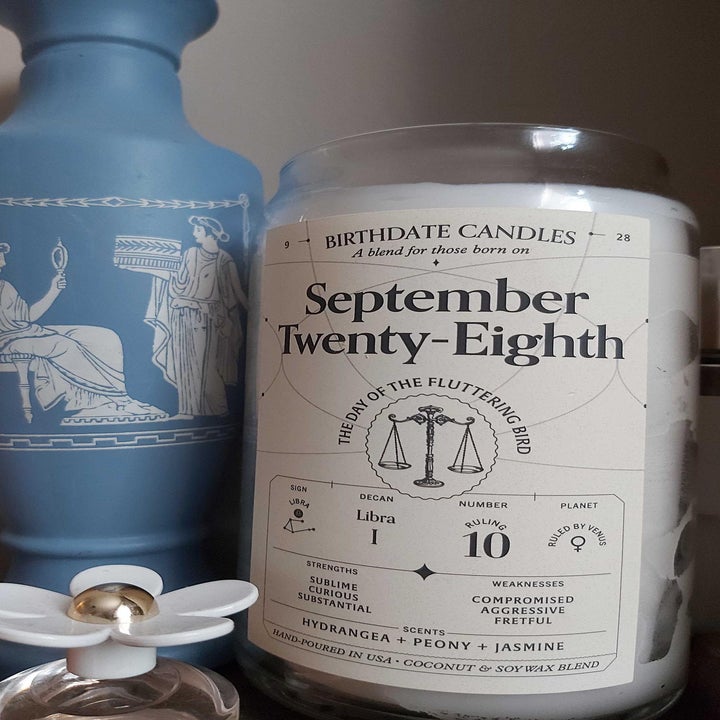 buzzfeeder's candle in a jar that says "september twenty-eighth, the day of the fluttering candle" with small astrological sign details for that date