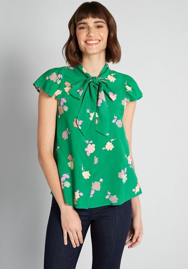 Model wearing the green cap sleeve blouse with pink and yellow flowers