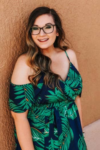 A reviewer wearing the navy cold-shoulder dress with green leaves