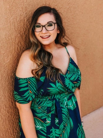 A reviewer wearing the navy cold-shoulder dress with green leaves