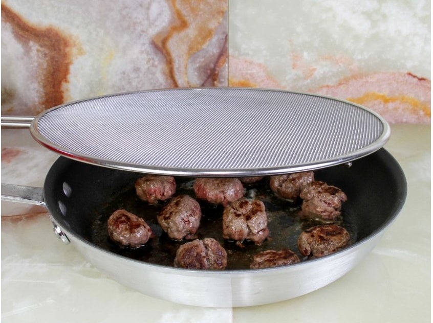 A 13-inch stainless steel, mesh splatter guard covering a pan of meatballs 