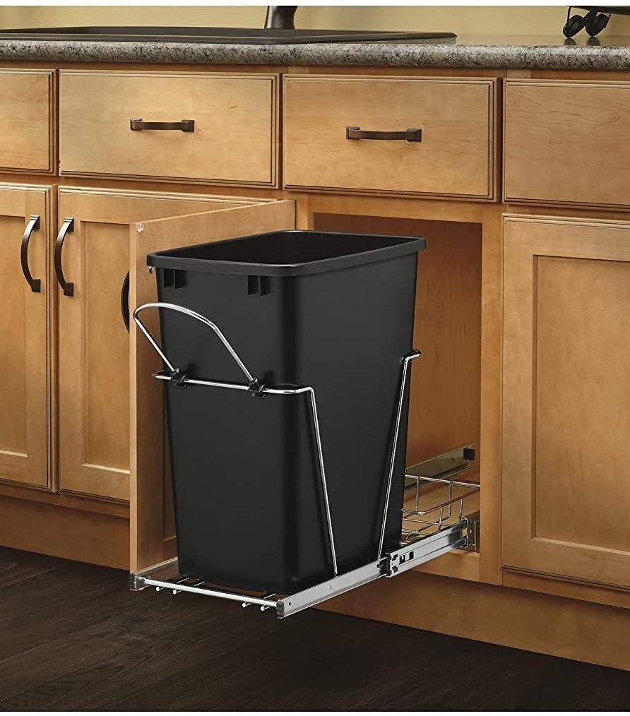 black trash can on metal track sliding out of cabinet