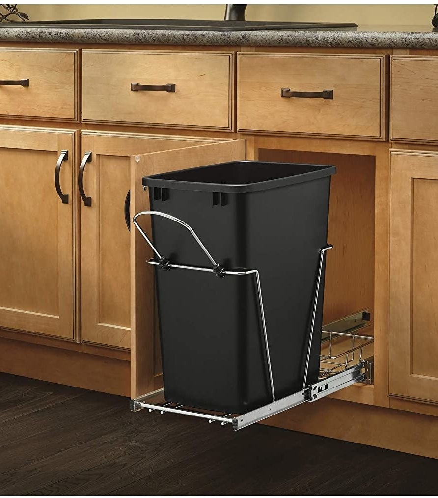 black trash can on metal track sliding out of cabinet