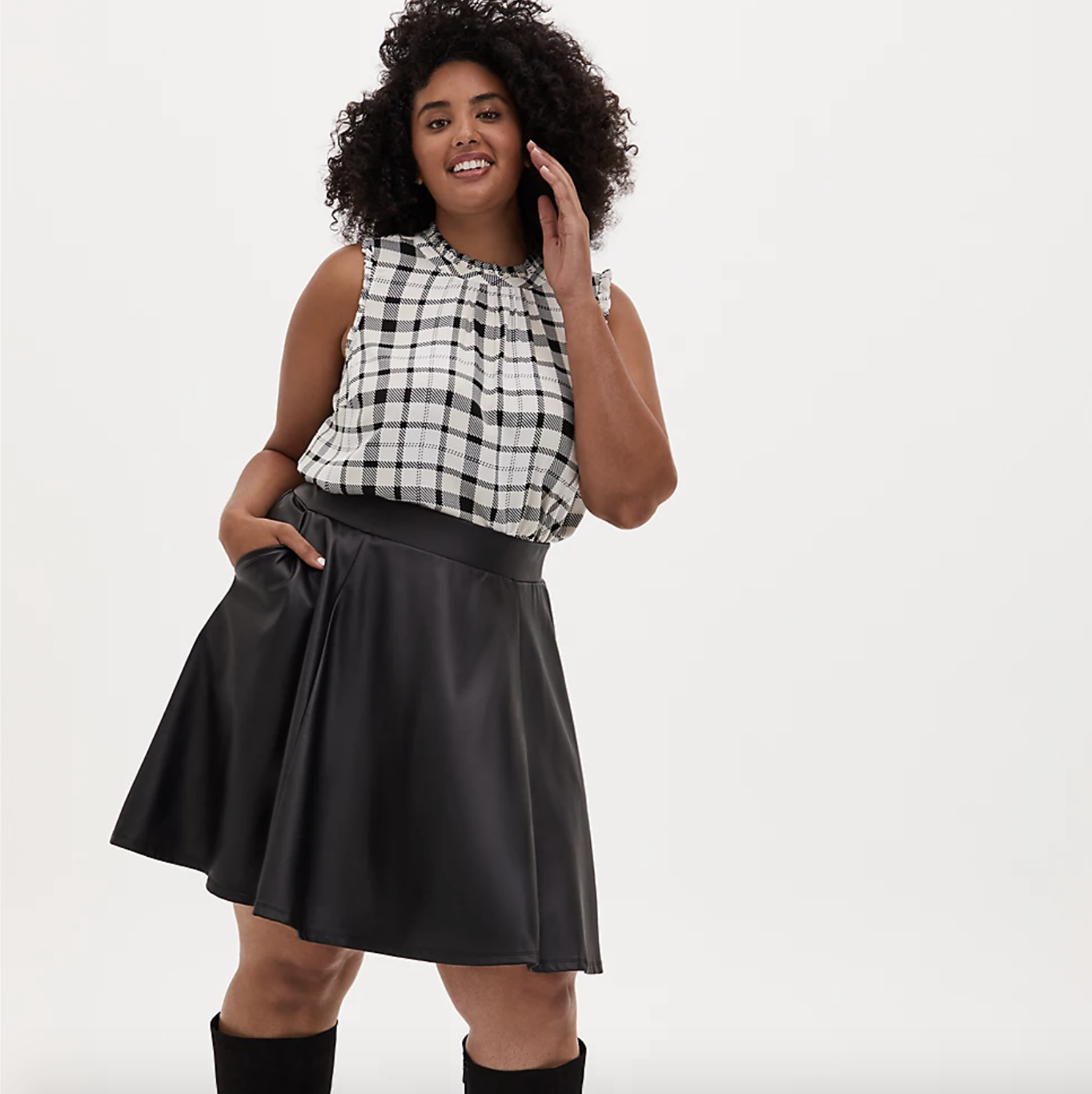 a plus size model wearing the black ponte skater mini skirt with a black and white sleeveless plaid top