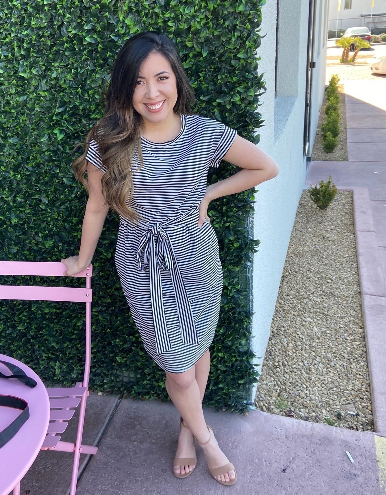 a reviewer wearing the dress with black and white stripes and the belt tied 