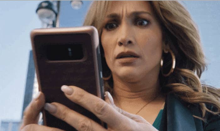 A woman stares at her phone with wide eyes