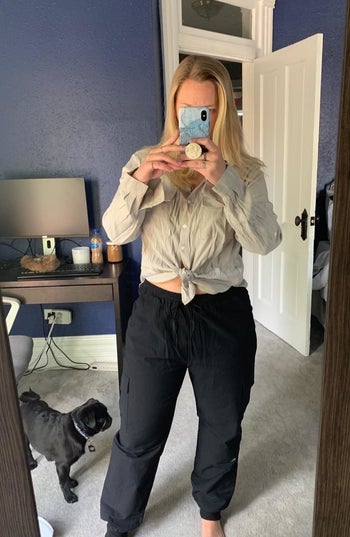 a reviewer wearing the shirt in tan buttoned-up and tied in the front 