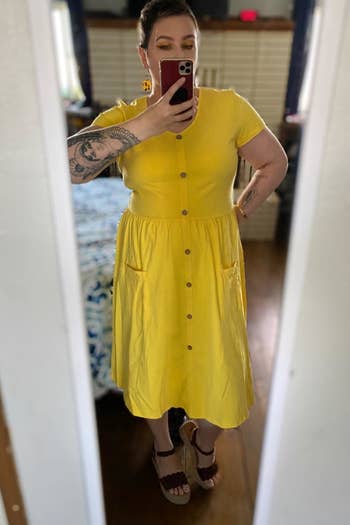 a reviewer mirror selfie of them wearing the yellow short-sleeved midi dress 
