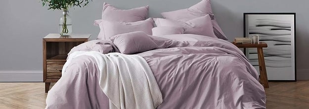 The cotton bedding set in dusty lavender next to two mismatched nightstand