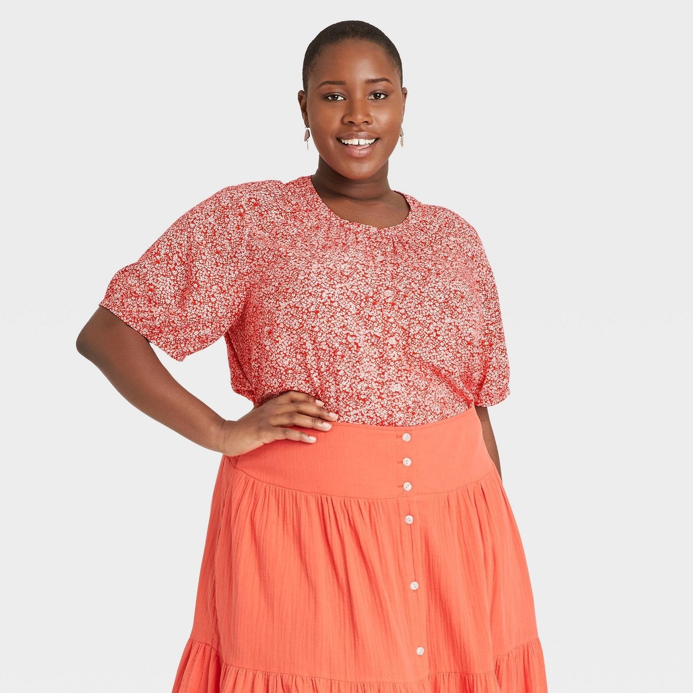 Model wearing orange button down blouse with round neck