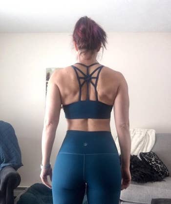 A reviewer wearing the sports bra in green from behind to show off the criss cross pattern 
