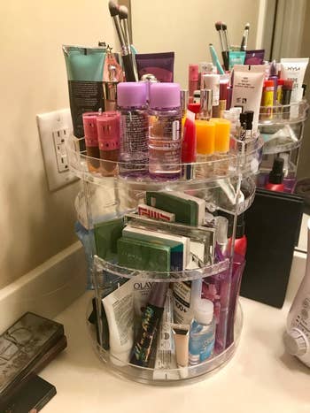 A reviewer photo of the makeup organizer filled with beauty products like lotion face wash makeup and more. 