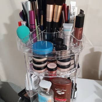 a reviewer photo of the makeup organizer filled with makeup lotion makeup brushes and more. 