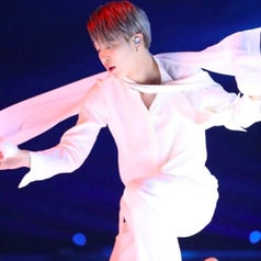 Jimin dances with a white piece of fabric, dressed all in white with silver hair