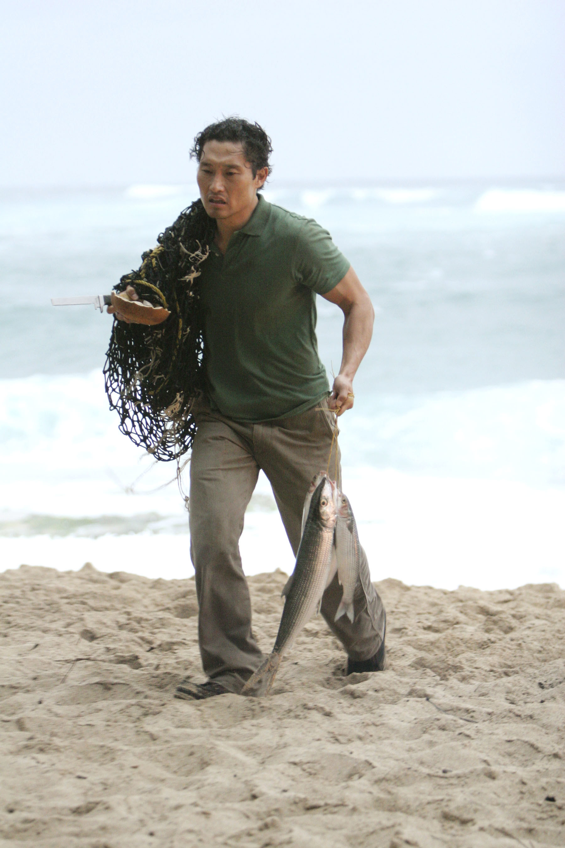 Kim carries a net and fish on the beach in the TV show Lost