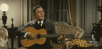Christopher as Captain von Trapp, strumming a guitar and singing