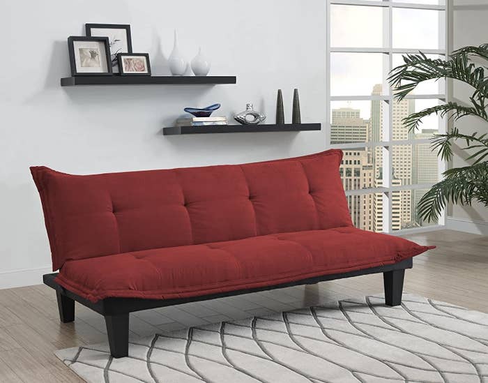 a red futon with a tufted back and seat