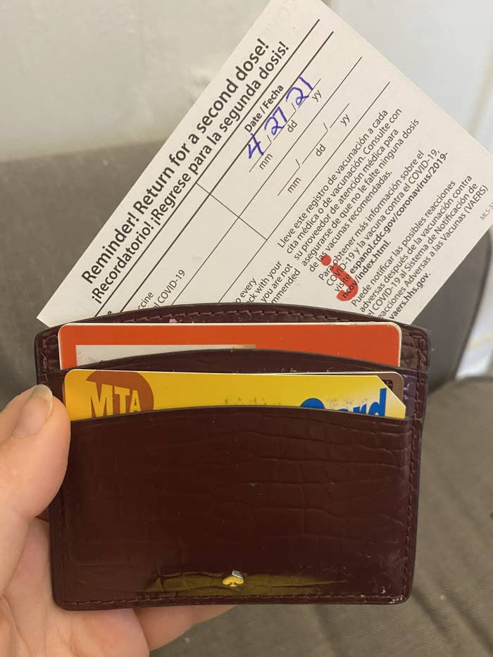 BuzzFeed editor attempting to put a too big vaccine card in a wallet 