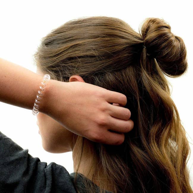model with top half of hair up in a messy bun and the phone cord-like band on wrist