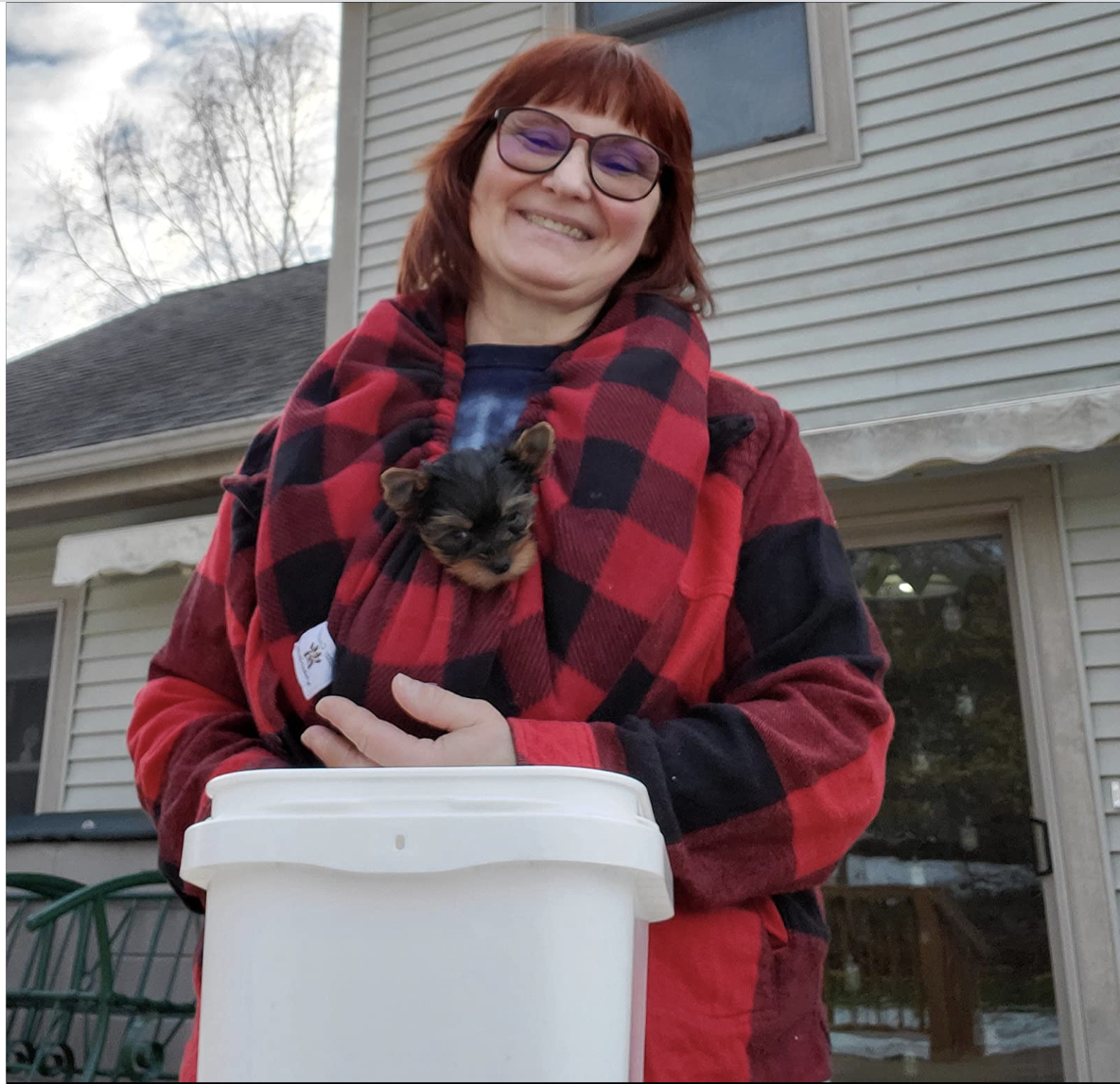 Reviewer wearing black and red gingham scarf with a Yorkie in it 