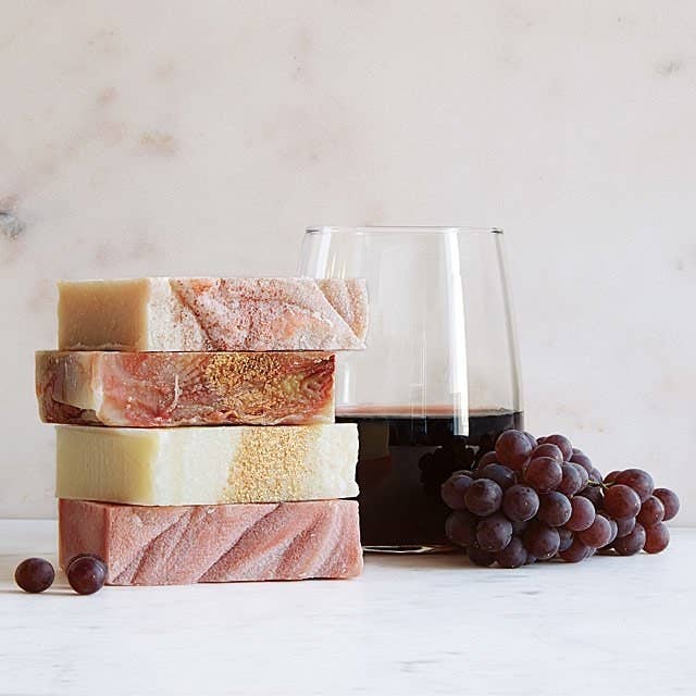 wine soaps stacked up next to glass of wine and grapes