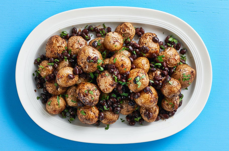 A big plate of roasted whole little potatoes with black beans and herbs.