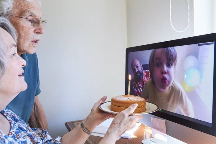 grandparents facetiming with grandkid with a cake as the child pretends to blow out candles