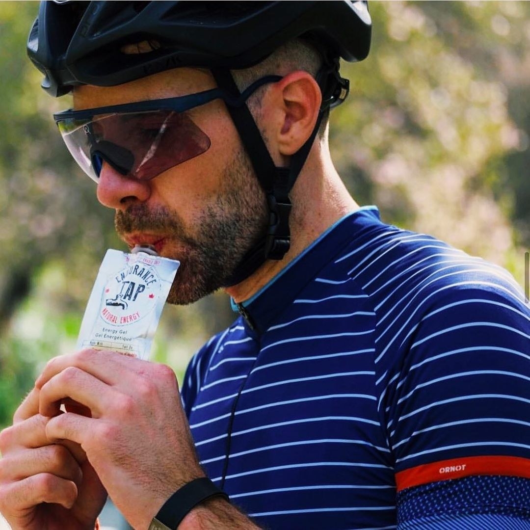 Someone squeezing the energy gel into their mouth while wearing full cycling gear