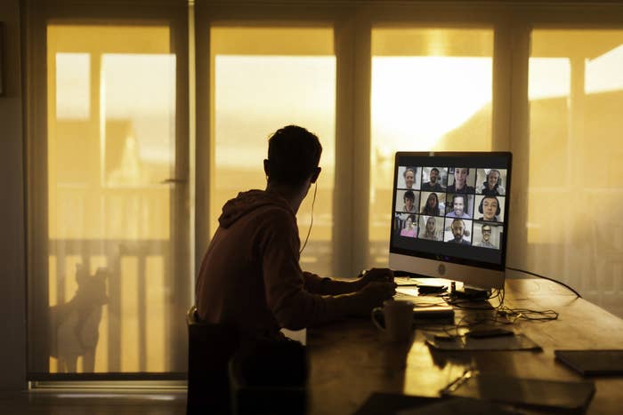 man in shadows looking out the window on a zoom call