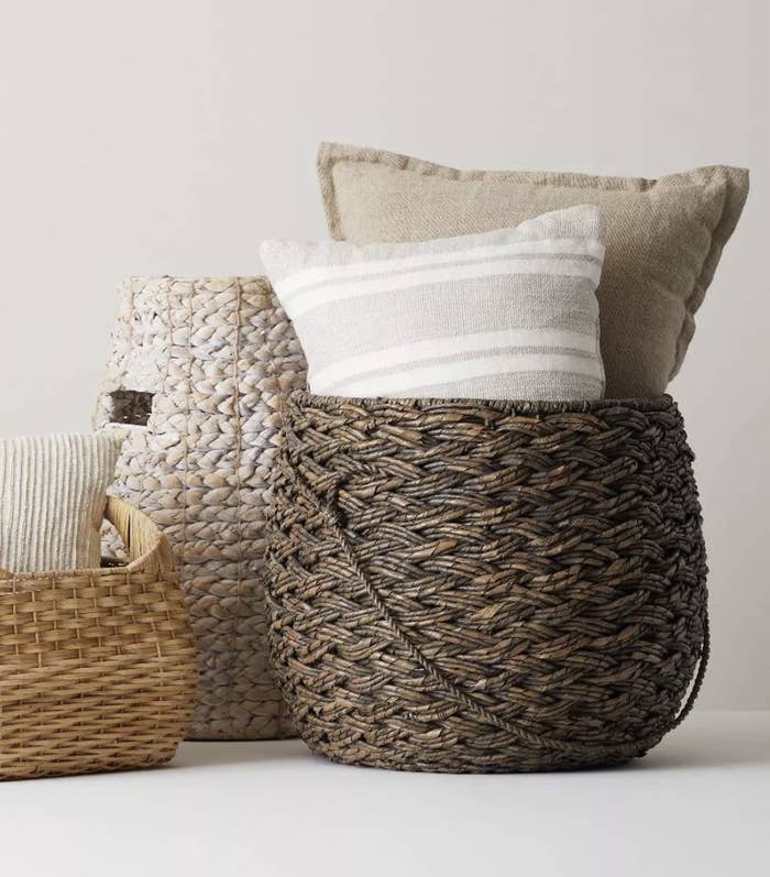 a large brown wicker basket holding pillows inside