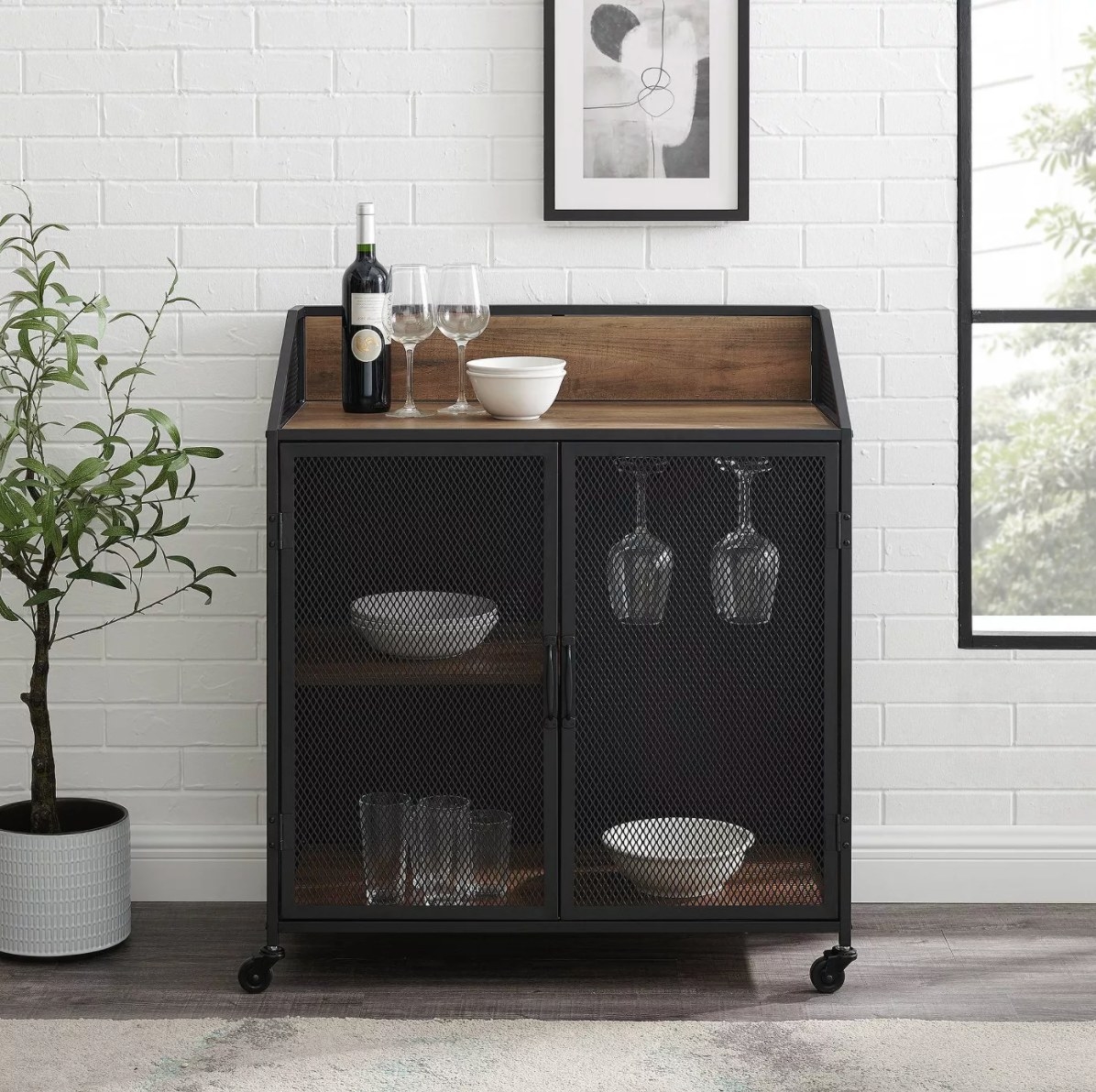 The industrial mesh cart in rustic oak holding wine glasses, a bottle of red, and white bowls