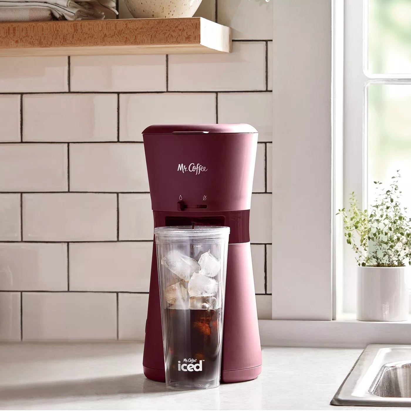 The iced coffee maker and the clear tumbler that comes with it on a kitchen counter