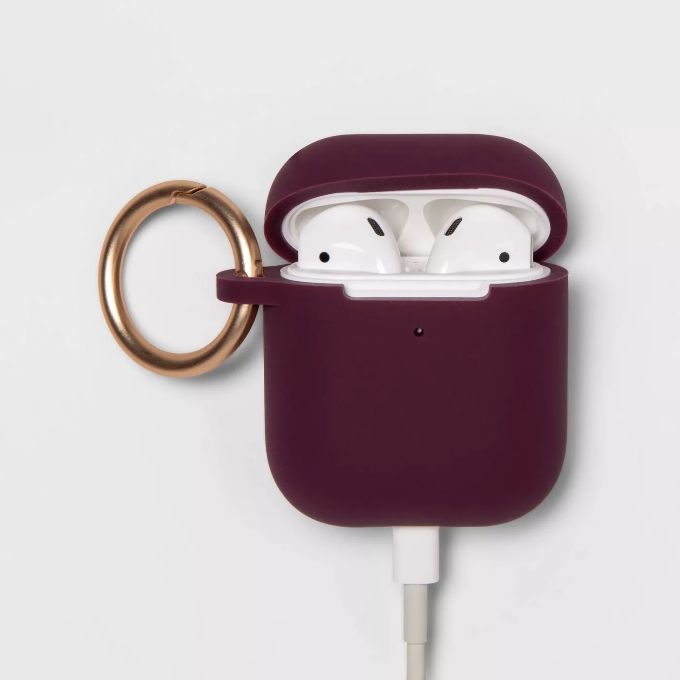 The Airpod case with Airpods inside and a gold carabiner clip