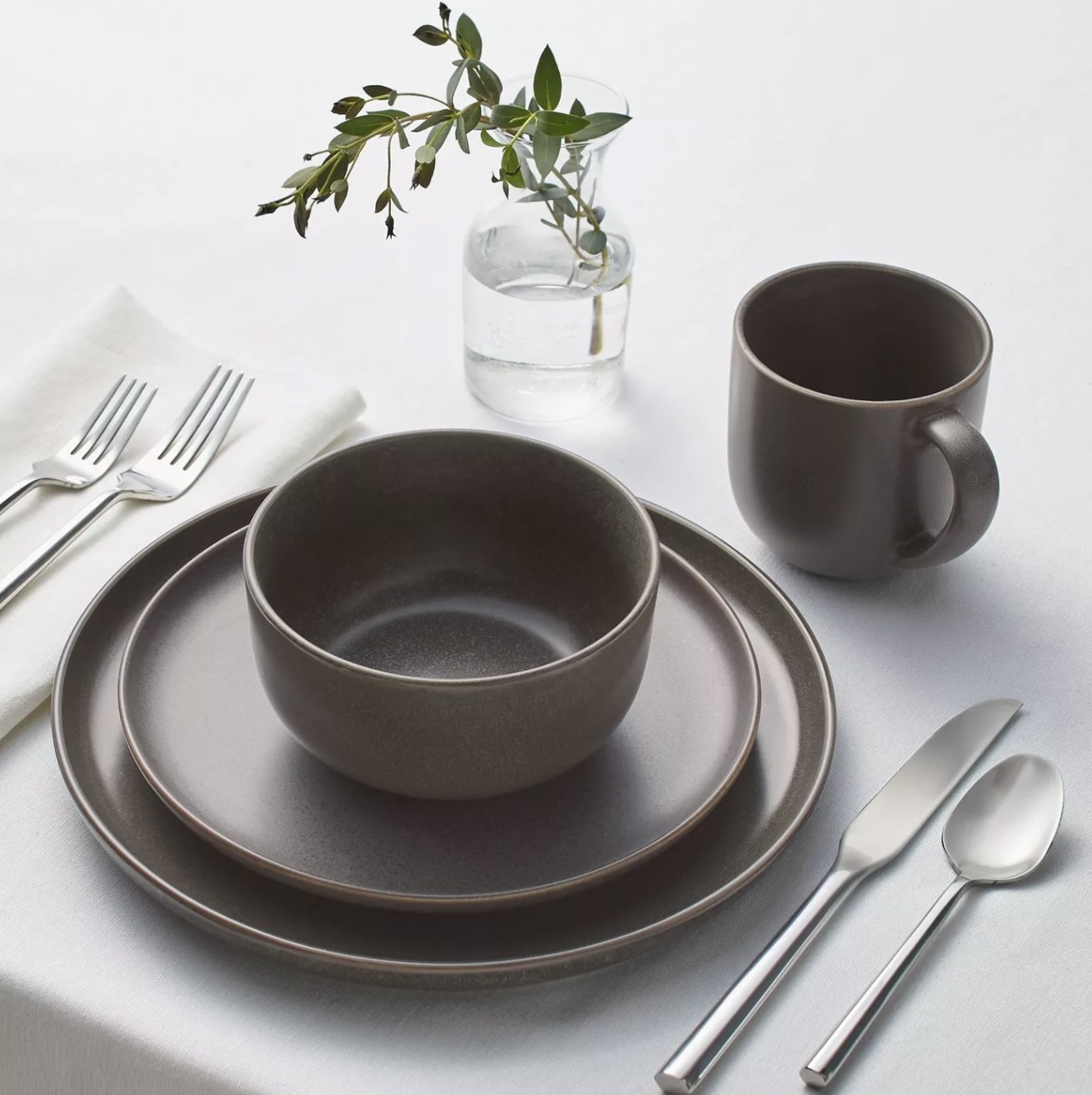 a brown stoneware mug, bowl, appetizer plate and dinner plate at a place setting 