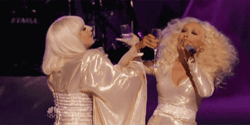 Gaga and Christina interlocking arms and sipping champagne as the lights dim