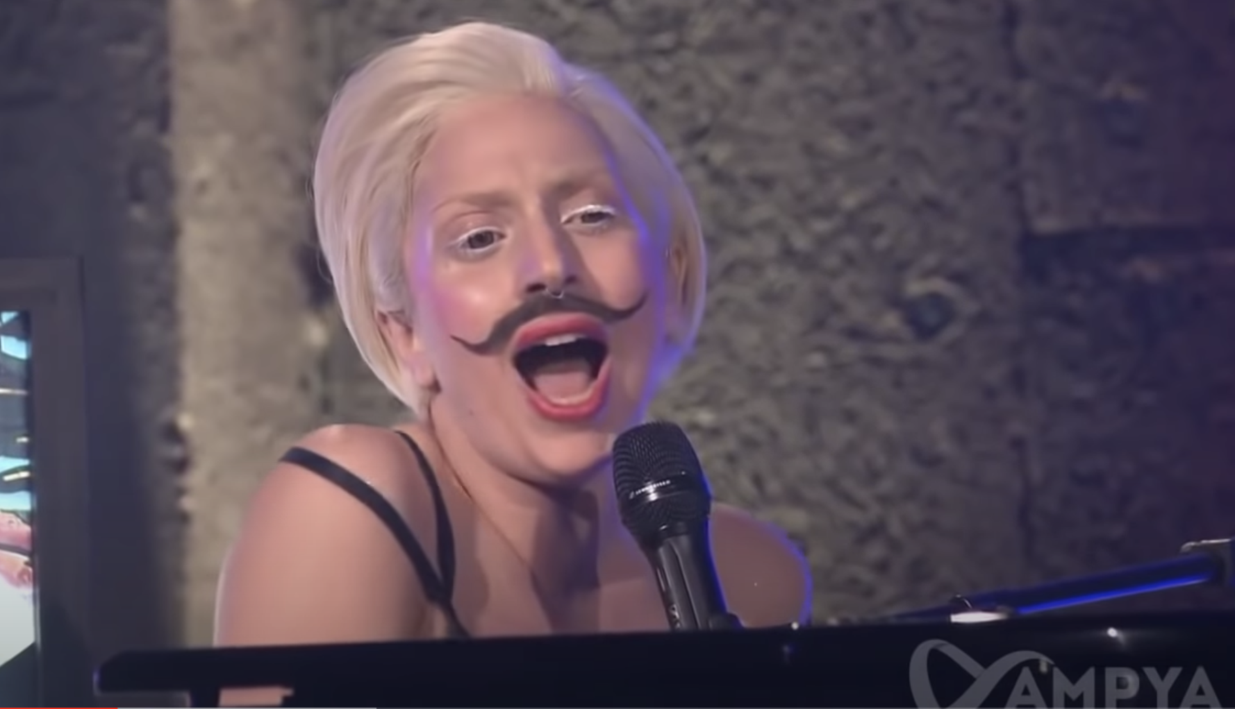 Gaga in white eyeliner and a fake handlebar mustache while at the piano singing Gypsy