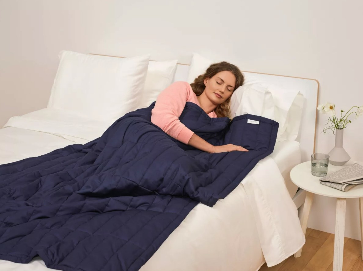 The Casper weighted blanket in navy blue being used by a model