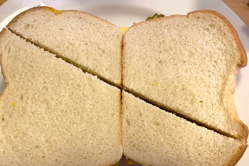 Two sandwiches cut diagonally where the halves are wildly different sizes
