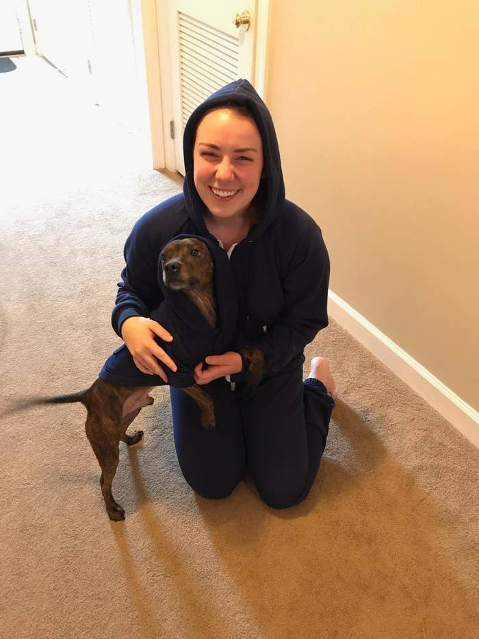 A dog and human wear the matching jogger onesies in dark blue