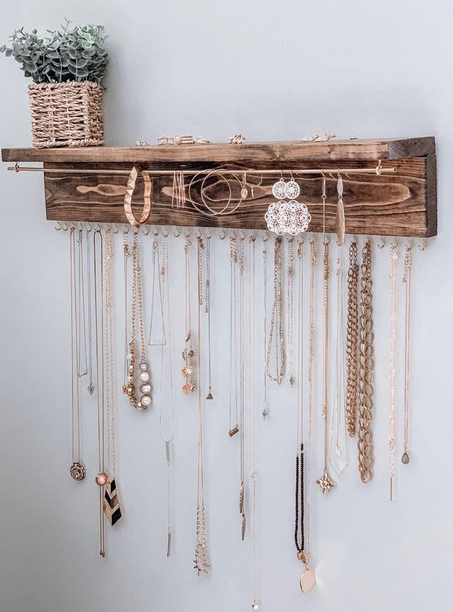 different necklaces, earrings, and bracelets hanging on the wooden wall-mounted organizer 
