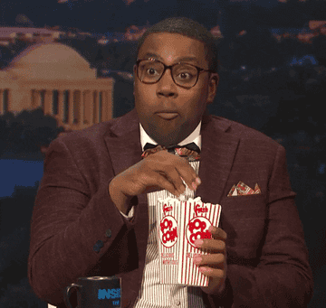 Kenan Thompson of SNL nodding and eating movie theater popcorn