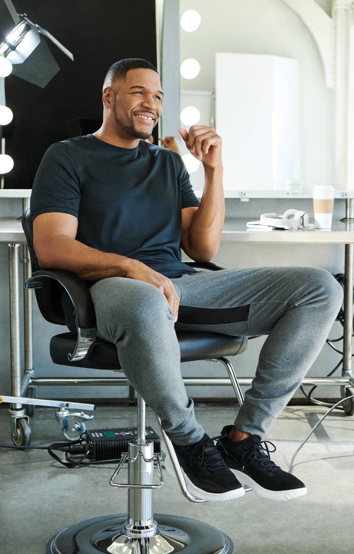 Michael Strahan wearing jogger paints and a T-shirt while sitting in a chair