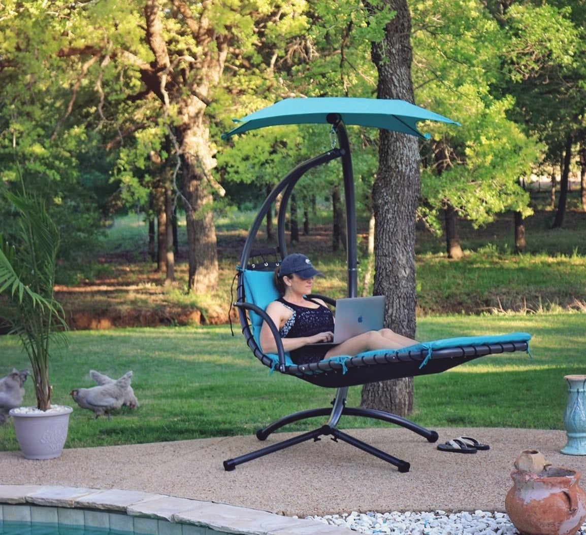 Reviewer sitting on the curved blue chair next to a pool