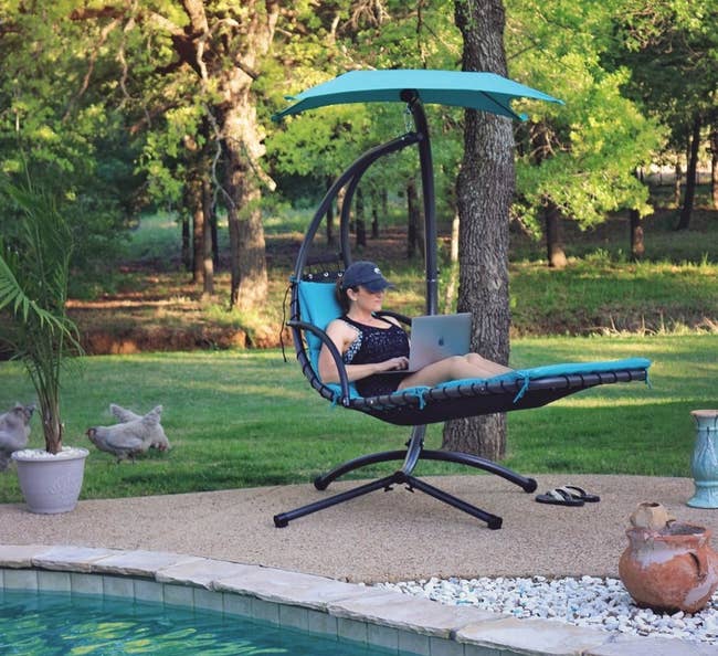Reviewer sitting on the curved blue chair next to a pool