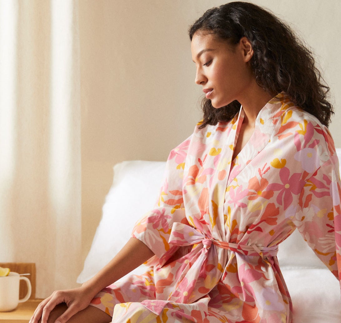 A person sitting on their bed while wearing the robe
